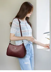 Detailaufnahme der weinroten Kroko-Schultertasche mit feiner Textur und eleganter Verarbeitung.