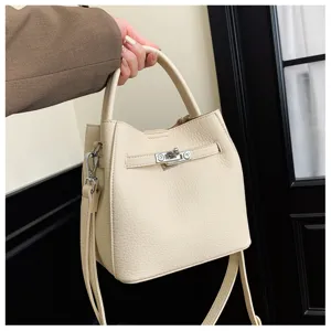 Stijlvolle elegante beige lederen emmertas voor dames met metalen sluiting en handvat.