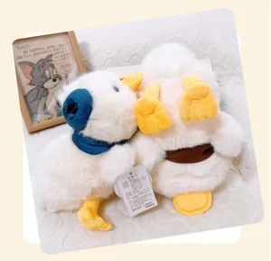 Cute white plush duck toy detail view, soft stuffed animal with blue scarf and yellow feet.