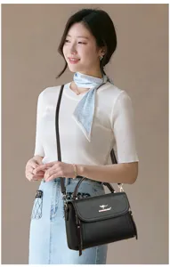 Detailansicht der stilvollen schwarzen Handtasche aus weichem Leder mit eleganter goldener Hardware.