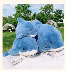 Plush blue dolphin toy detailed view, soft stuffed animal pillow on outdoor book prop.