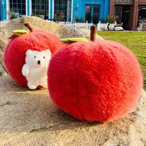 Close-up detail of cute red apple plush pillow with lovely white animal toy outdoors.