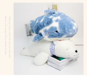 Cute blue tie-dye shark and white seal plush toys resting on books, soft ocean series pillow.
