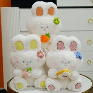 Simpatico coniglietto di peluche con orecchie sedute e bambola con carota e fragola.