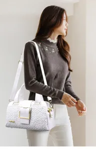 Borsa a mano bianca in coccodrillo goffrato con elegante motivo floreale e dettagli oro.