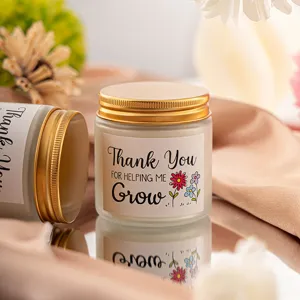 Vela aromática de vidrio esmerilado con tapa dorada y etiqueta de agradecimiento para regalo.