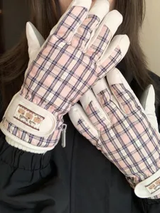 Gros plan détail de gants de ski imperméables à carreaux roses avec doublure en peluche et sangle.