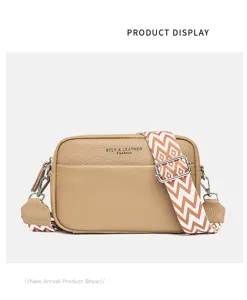 Detailed view of genuine leather crossbody bag with wide ethnic strap and gold metal hardware.