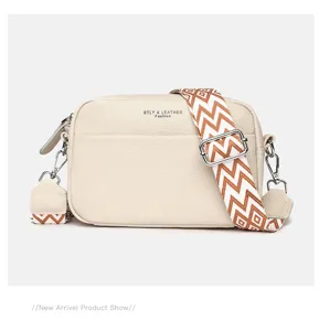 Detail view of stylish genuine leather crossbody bag with wide woven strap and metal hardware.
