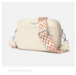 Detailed close-up view of cream leather crossbody camera bag featuring wide geometric shoulder strap.