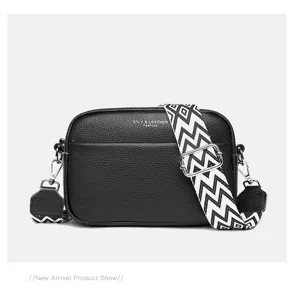 Genuine leather crossbody bag detail showcasing contrast geometric wide strap and metal hardware.