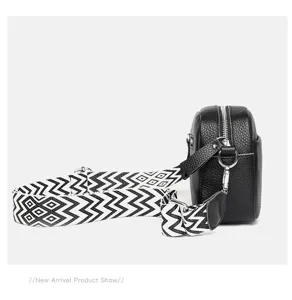 Black genuine leather crossbody bag detail showing geometric strap and metal hardware.