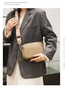 Genuine leather crossbody bag detail, compact square shape with wide geometric strap.