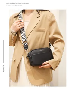 Black leather crossbody bag detail view, compact square shape with stylish wide strap.