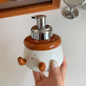 Cute ceramic foaming soap dispenser with cartoon face and pump, ideal for bathroom lotion storage.