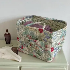 Detailed close-up view of the quilted floral storage basket featuring handles and front pocket.