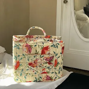 Quilted floral fabric storage basket with handle and pocket for home organization.