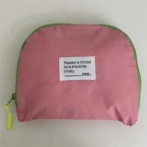 Rosa reise aufbewahrungstasche detail mit grünem reißverschluss und text etikett, tägliche tasche.