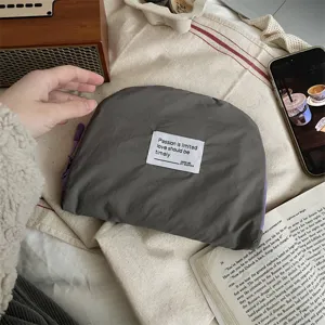 Detailaufnahme der grauen Kosmetiktasche mit Stoffetikett und praktischem Reißverschluss.