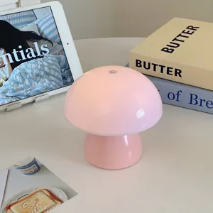 Close-up detail of a cute pink mushroom touch night lamp on a cozy white desk setup.