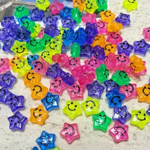 Gros plan de perles étoiles en acrylique coloré avec visage souriant, bijoux DIY.