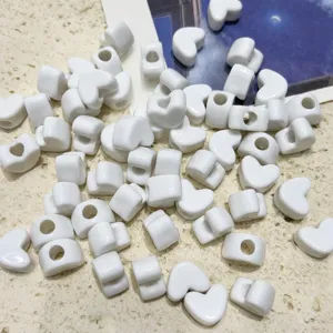 Detail shot of white heart-shaped acrylic loose beads with hole, perfect for DIY jewelry making.