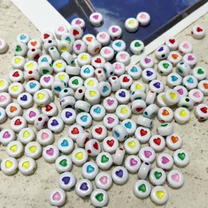 Close-up of white acrylic loose beads with colorful heart patterns for DIY jewelry making.
