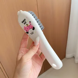 Close-up detail of white household cleaning laundry brush with cute cat graphic design.
