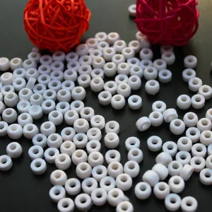 Close-up detail shot of white acrylic barrel beads, scattered loose beads for DIY crafts.