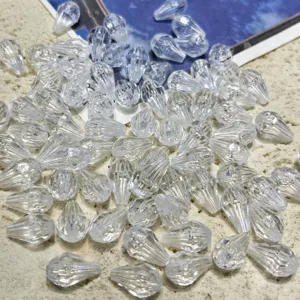 Clear acrylic teardrop beads 8x12mm closeup, transparent hanging crystal charms for jewelry DIY.