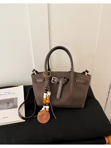 Sac à main marron texturé avec pendentif en perles, élégant sac porté épaule pour femmes.