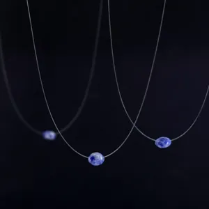 Detail shot of the invisible fishing line floating necklace featuring a blue gemstone pendant.