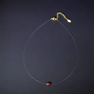 Detailed view of the clear fishing line choker necklace featuring an oval red stone pendant.