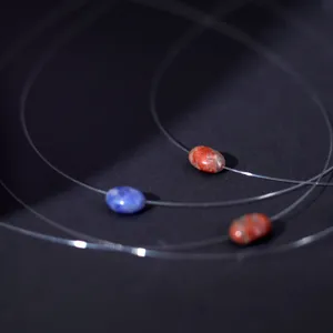 Detailed shot of invisible fishing line necklace with colorful oval natural stone pendants.