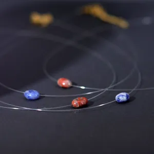 Close-up detail of invisible fishing line floating necklace with natural red and blue stone beads.