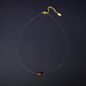 Invisible fishing line necklace featuring an oval red stone pendant and gold extension chain.