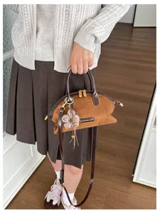 Vue détaillée d'un sac bandoulière rétro en daim marron avec pendentif fleur en tricot.