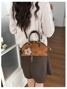 Détail de sac à main rétro en suédine marron avec design coquillage et charm fleur.