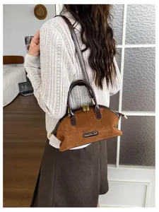 Vue de détail d'un sac à main rétro en daim marron avec poignées et bandoulière élégante.