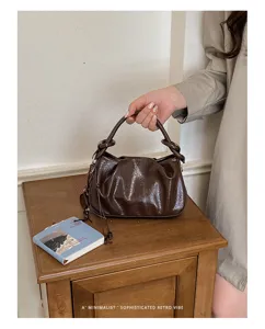 Vue détaillée du sac à main marron plissé élégant montrant sa texture brillante et rétro.