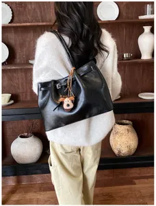 Detail view of the black leather shoulder tote bag featuring a cute dog pendant charm.