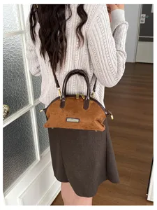 Vue détaillée du sac à main rétro en daim marron avec texture douce et quincaillerie en métal.