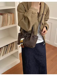 Vue détaillée du sac seau marron foncé effet croco avec boucle et pendentif en perles.