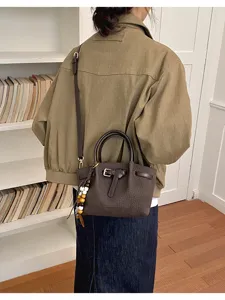 Sac à main élégant motif crocodile marron avec bandoulière et pendentif perles chic.