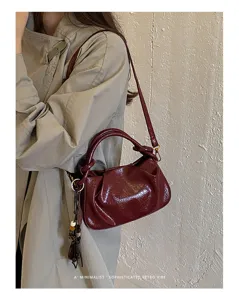 Vue détaillée du sac à main plissé bordeaux élégant, texture brillante et style chic.