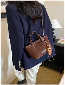 Retro suede crossbody bag for women, chic shoulder tote with beaded pendant and top handle.