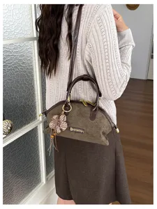 Sac coquillage en suédine rétro, vue détaillée avec charmant pendentif fleur et poignée.