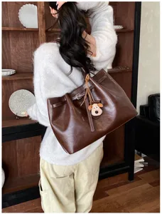 Close up view of the brown leather tote bag detail, featuring retro shoulder strap design.