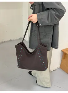 Bolso tote de hombro marrón grande con detalles de remaches azules para el uso diario casual.
