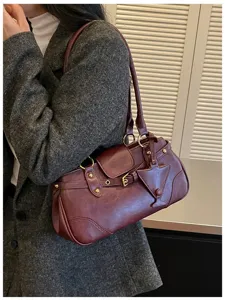 Detail view of the vintage burgundy leather shoulder bag with chic metal buckle and strap.
